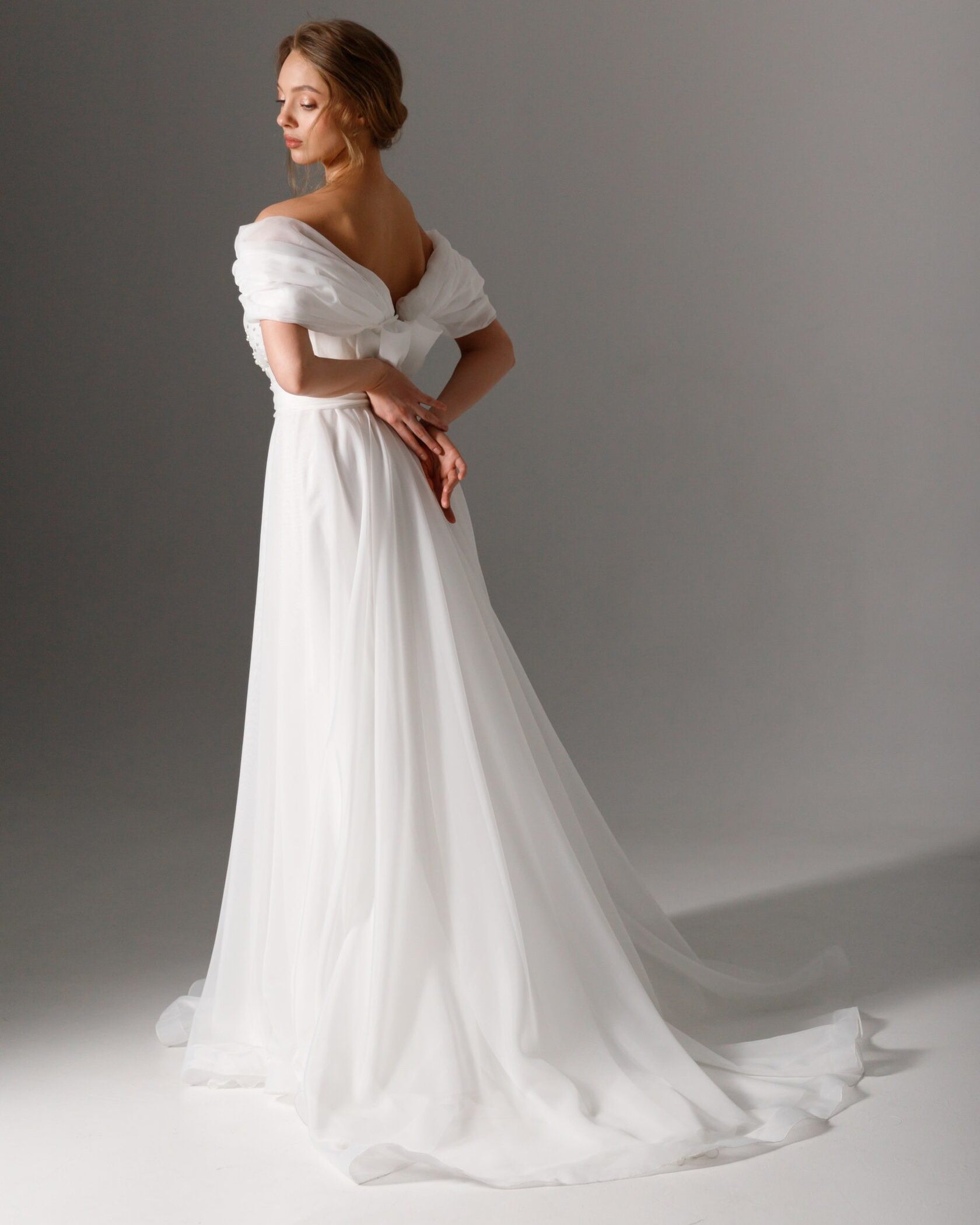 Delicate pearl-detailed wedding dress with a draped bodice and lightweight skirt