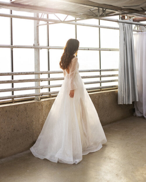 Elegant sheer wedding gown featuring subtle sparkle and a modern minimalist design