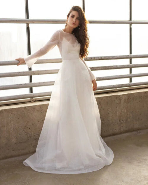 Minimalist glitter long sleeve wedding dress with sheer overlay and flowing A-line silhouette