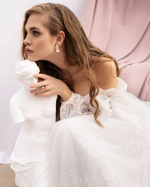 Off-the-shoulder lace corset wedding dress with voluminous sleeves and a flowing tulle skirt