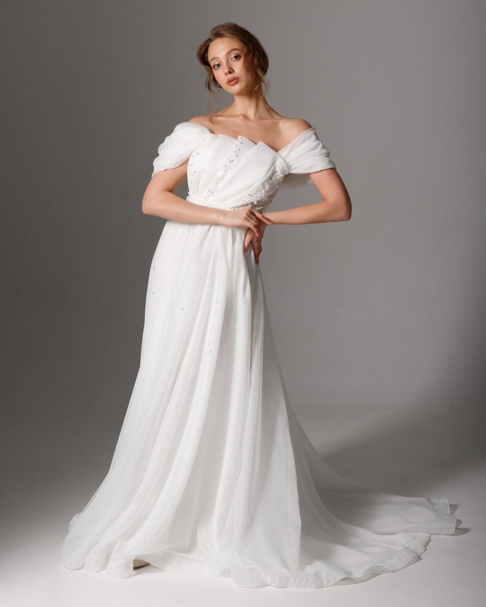 Off-the-shoulder pearl-embellished wedding dress with a flowing A-line silhouette