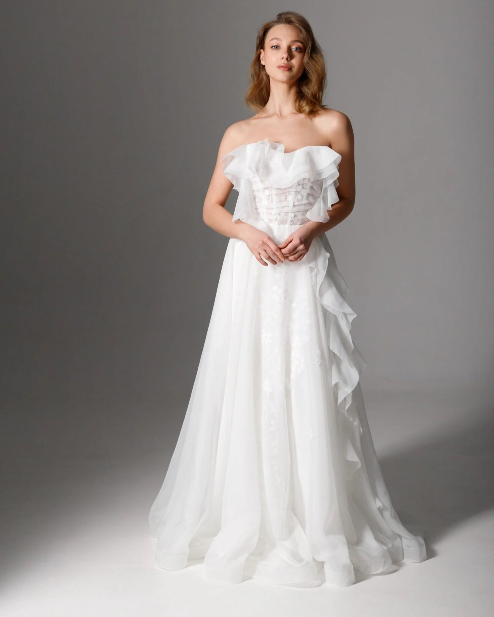 Romantic sheer organza wedding gown with a strapless ruffled corset bodice and A-line silhouette